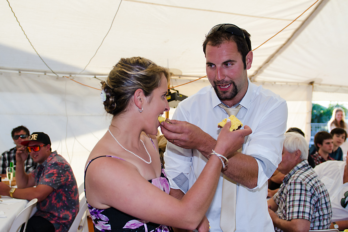 bride and groom cutting and eatinfg wedding cake